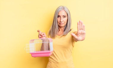 Orta yaşlı, güzel bir kadın ciddi görünüyor. Avuç içini gösteriyor. Durdurma hareketi yapıyor. evcil hayvan kafesi veya hapishane konsepti