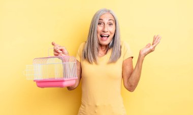 Orta yaşlı, güzel bir kadın inanılmaz bir şey karşısında mutlu ve şaşkın hissediyor. evcil hayvan kafesi veya hapishane konsepti