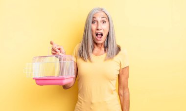 Orta yaşlı güzel bir kadın çok şaşırmış ya da şaşkın görünüyor. evcil hayvan kafesi veya hapishane konsepti