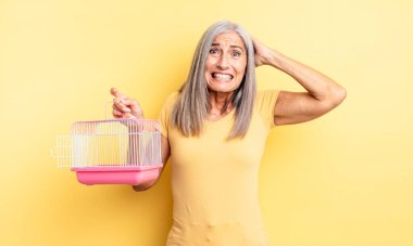 Orta yaşlı, güzel bir kadın stresli, endişeli ya da korkmuş, elleri başının üstünde. evcil hayvan kafesi veya hapishane konsepti