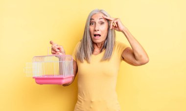 Orta yaşlı, güzel bir kadın mutlu, şaşkın ve şaşırmış görünüyor. evcil hayvan kafesi veya hapishane konsepti