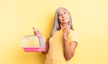 Orta yaşlı, güzel bir kadın kibirli, başarılı, pozitif ve gururlu görünüyor. evcil hayvan kafesi veya hapishane konsepti