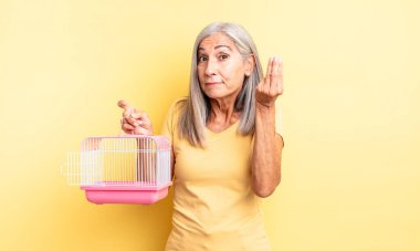 Orta yaşlı, güzel bir kadın kapiş ya da para hareketi yapıp sana ödemeni söylüyor. evcil hayvan kafesi veya hapishane konsepti