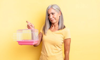 Orta yaşlı, güzel bir kadın üzgün, üzgün ya da kızgın ve yana bakıyor. evcil hayvan kafesi veya hapishane konsepti