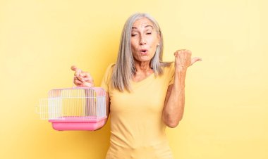 Orta yaşlı, güzel bir kadın inançsızlıktan şaşkın şaşkın bakıyor. evcil hayvan kafesi veya hapishane konsepti