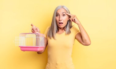 Orta yaşlı, güzel bir kadın şaşırmış görünüyor, yeni bir düşünce, fikir ya da konsept fark ediyor. evcil hayvan kafesi veya hapishane konsepti