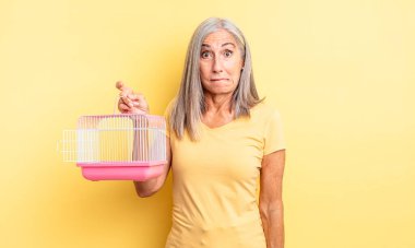 Orta yaşlı güzel bir kadın kafası karışmış ve şaşkın görünüyor. evcil hayvan kafesi veya hapishane konsepti