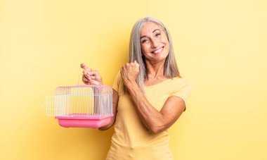 Orta yaşlı, güzel bir kadın kendini mutlu hisseder ve bir meydan okumayla yüzleşir ya da kutlama yapar. evcil hayvan kafesi veya hapishane konsepti