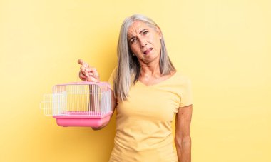Orta yaşlı, güzel bir kadın şaşkın ve kafası karışık hissediyor. evcil hayvan kafesi veya hapishane konsepti