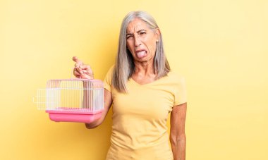 Orta yaşlı, güzel bir kadın iğreniyor, sinirleniyor ve dili dışarı çıkıyor. evcil hayvan kafesi veya hapishane konsepti