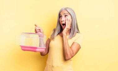 Orta yaşlı, güzel bir kadın mutlu, heyecanlı ve şaşırmış hissediyor. evcil hayvan kafesi veya hapishane konsepti