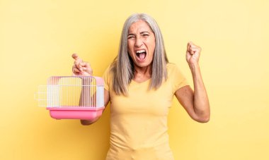 Orta yaşlı, güzel bir kadın sinirli bir ifadeyle agresif bir şekilde bağırıyor. evcil hayvan kafesi veya hapishane konsepti