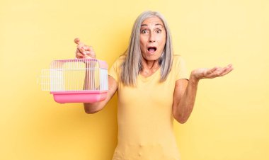 Orta yaşlı güzel bir kadın son derece şaşkın ve şaşırmış hissediyor. evcil hayvan kafesi veya hapishane konsepti