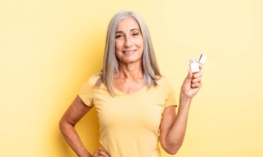 Orta yaşlı güzel bir kadın mutlu bir şekilde gülümsüyor, eli kalçasında ve kendinden emin. daha hafif kavram