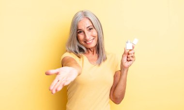 Orta yaşlı, güzel bir kadın arkadaşça gülümsüyor ve bir konsept sunuyor. daha hafif kavram