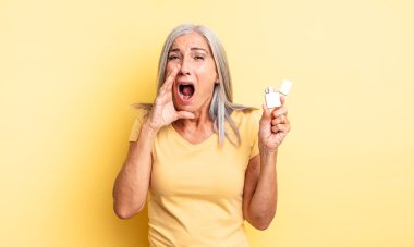 Orta yaşlı, güzel bir kadın kendini mutlu hissediyor. Elleri ağzının kenarında bağırıyor. daha hafif kavram