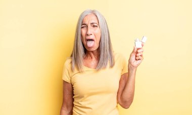 Orta yaşlı, neşeli ve asi tavırları olan, şaka yapan ve dilini dışarı çıkaran güzel bir kadın. daha hafif kavram