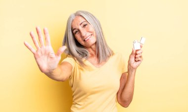 Orta yaşlı güzel bir kadın gülümsüyor ve arkadaş canlısı görünüyor, beş numarayı gösteriyor. daha hafif kavram