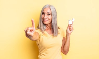 Orta yaşlı güzel bir kadın gülümsüyor ve arkadaş canlısı görünüyor. Bir numarayı gösteriyor. daha hafif kavram