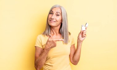 Orta yaşlı güzel bir kadın neşeli bir şekilde gülümsüyor, mutlu hissediyor ve bir tarafı işaret ediyor. daha hafif kavram