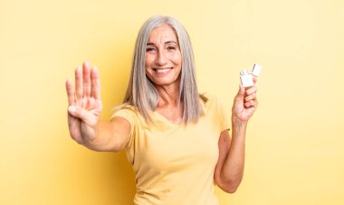 Orta yaşlı güzel bir kadın gülümsüyor ve arkadaş canlısı görünüyor, dört numarayı gösteriyor. daha hafif kavram