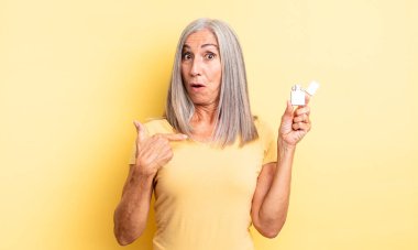 Orta yaşlı güzel bir kadın şok olmuş ve ağzı açık, kendini işaret eden bir şekilde şaşırmış görünüyor. daha hafif kavram