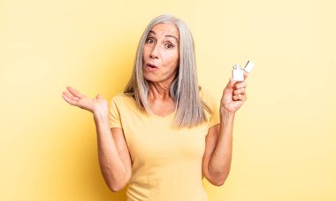 Orta yaşlı, güzel bir kadın şaşırmış ve şok olmuş görünüyor. Çenesi düşmüş ve elinde bir nesne var. daha hafif kavram