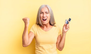 Orta yaşlı, güzel bir kadın sinirli bir ifadeyle agresif bir şekilde bağırıyor. daha hafif kavram