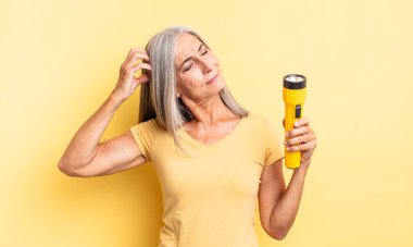 Orta yaşlı, güzel bir kadın şaşkın ve kafası karışık, kaşınıyor. fener konsepti