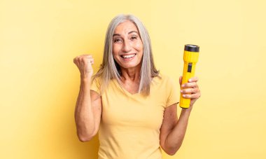 Orta yaşlı, güzel bir kadın şokta, gülüyor ve başarıyı kutluyor. fener konsepti