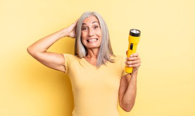 Orta yaşlı, güzel bir kadın stresli, endişeli ya da korkmuş, elleri başının üstünde. fener konsepti