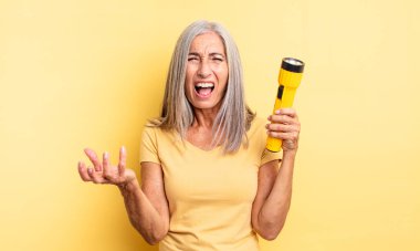 Orta yaşlı, güzel bir kadın sinirli, sinirli ve sinirli görünüyor. fener konsepti