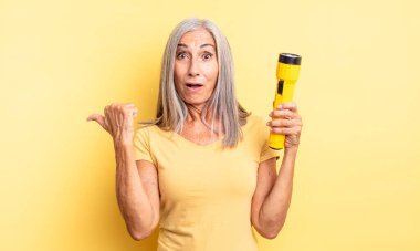 Orta yaşlı, güzel bir kadın inançsızlıktan şaşkın şaşkın bakıyor. fener konsepti