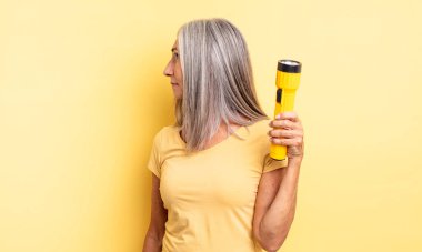 Profil görünümlü orta yaşlı güzel bir kadın hayal kuruyor ya da hayal kuruyor. fener konsepti