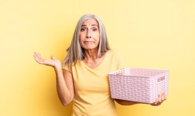 Orta yaşlı, güzel bir kadın şaşkın, şaşkın ve şüpheci hissediyor. boş sepet konsepti