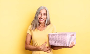 Orta yaşlı güzel bir kadın komik bir şakaya yüksek sesle gülüyor. boş sepet konsepti