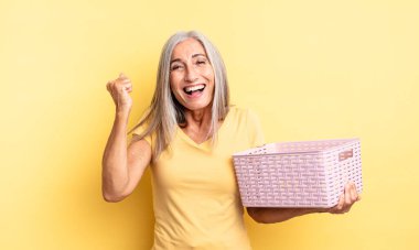 Orta yaşlı, güzel bir kadın şokta, gülüyor ve başarıyı kutluyor. boş sepet konsepti