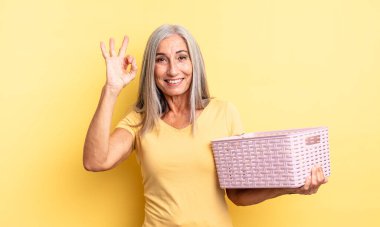 Orta yaşlı, güzel bir kadın kendini mutlu hissediyor, iyi bir jestle onaylıyor. boş sepet konsepti