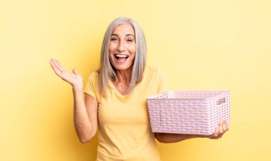 Orta yaşlı, güzel bir kadın inanılmaz bir şey karşısında mutlu ve şaşkın hissediyor. boş sepet konsepti