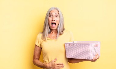 Orta yaşlı güzel bir kadın çok şaşırmış ya da şaşkın görünüyor. boş sepet konsepti