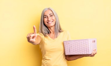 Orta yaşlı, güzel bir kadın gururla gülümsüyor ve kendinden emin bir numara oluyor. boş sepet konsepti