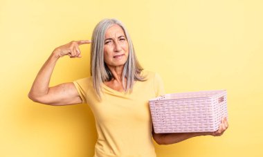 Orta yaşlı güzel bir kadın kafası karışık ve şaşkın hissediyor, deli olduğunu gösteriyor. boş sepet konsepti
