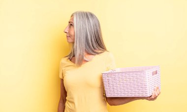 Profil görünümlü orta yaşlı güzel bir kadın hayal kuruyor ya da hayal kuruyor. boş sepet konsepti