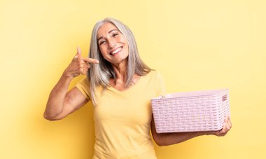 Orta yaşlı, güzel bir kadın, kendine güvenerek gülümsüyor. boş sepet konsepti