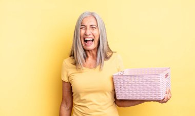Orta yaşlı, güzel bir kadın agresif bir şekilde bağırıyor, çok kızgın görünüyor. boş sepet konsepti