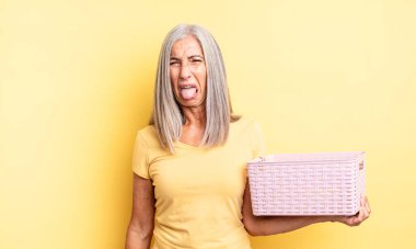 Orta yaşlı, güzel bir kadın iğreniyor, sinirleniyor ve dili dışarı çıkıyor. boş sepet konsepti