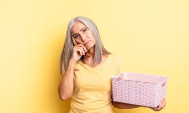 Orta yaşlı, güzel bir kadın bıkkın, yorgun ve uykulu hissediyor. boş sepet konsepti