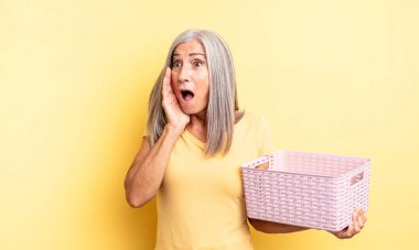 Orta yaşlı, güzel bir kadın mutlu, heyecanlı ve şaşırmış hissediyor. boş sepet konsepti