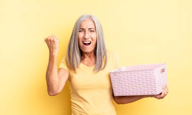 Orta yaşlı, güzel bir kadın sinirli bir ifadeyle agresif bir şekilde bağırıyor. boş sepet konsepti