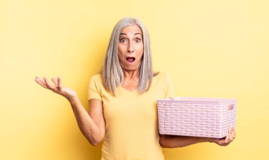 Orta yaşlı güzel bir kadın son derece şaşkın ve şaşırmış hissediyor. boş sepet konsepti